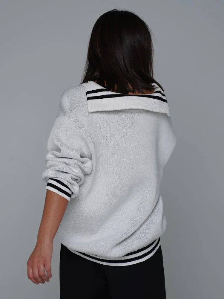 Woman wearing a red knit sweater with CCCP graphic print and black stripes on cuffs and hem.