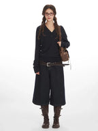 Woman wearing a navy long-sleeve henley shirt and dark wash wide-leg culottes.
