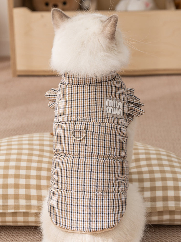 Back view of a cat wearing a brown plaid pet vest with ruffled sleeves and a leash ring.
