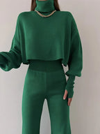 Woman wearing a green knit turtleneck crop top with balloon sleeves and matching green knit pants.