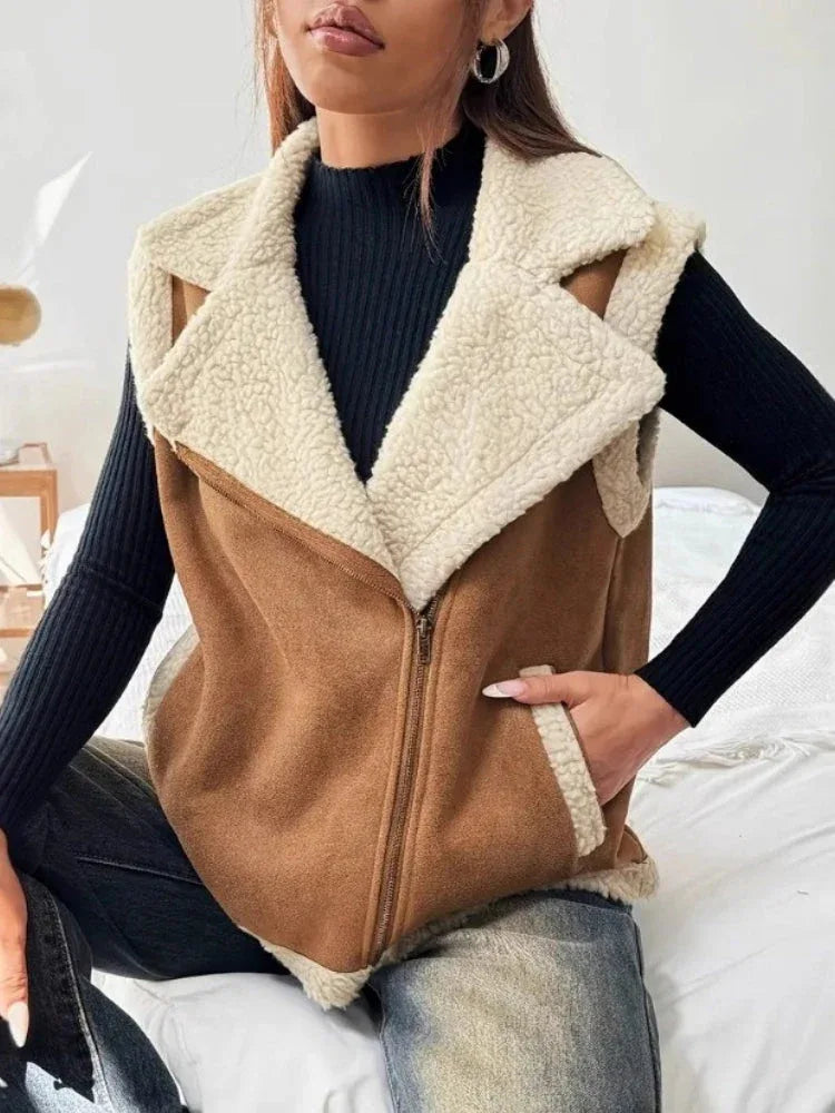 Woman wearing a brown faux suede vest with cream faux shearling lining and trim, zipped closed.