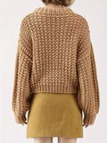 Back view of a woman in a tan chunky knit sweater with balloon sleeves and a mock neckline.
