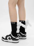 Close-up of black crew socks with a plush white bunny charm and 'MSE' logo on the back.