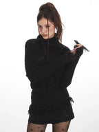 Close-up of a woman wearing a black turtleneck sweater, showing the textured fabric and fringed cuffs