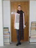 Woman wearing a plaid scarf, pink long-sleeve top, grey patterned tights, and a white skirt