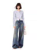 Woman wearing a light blue knit cardigan and wide-leg jeans.