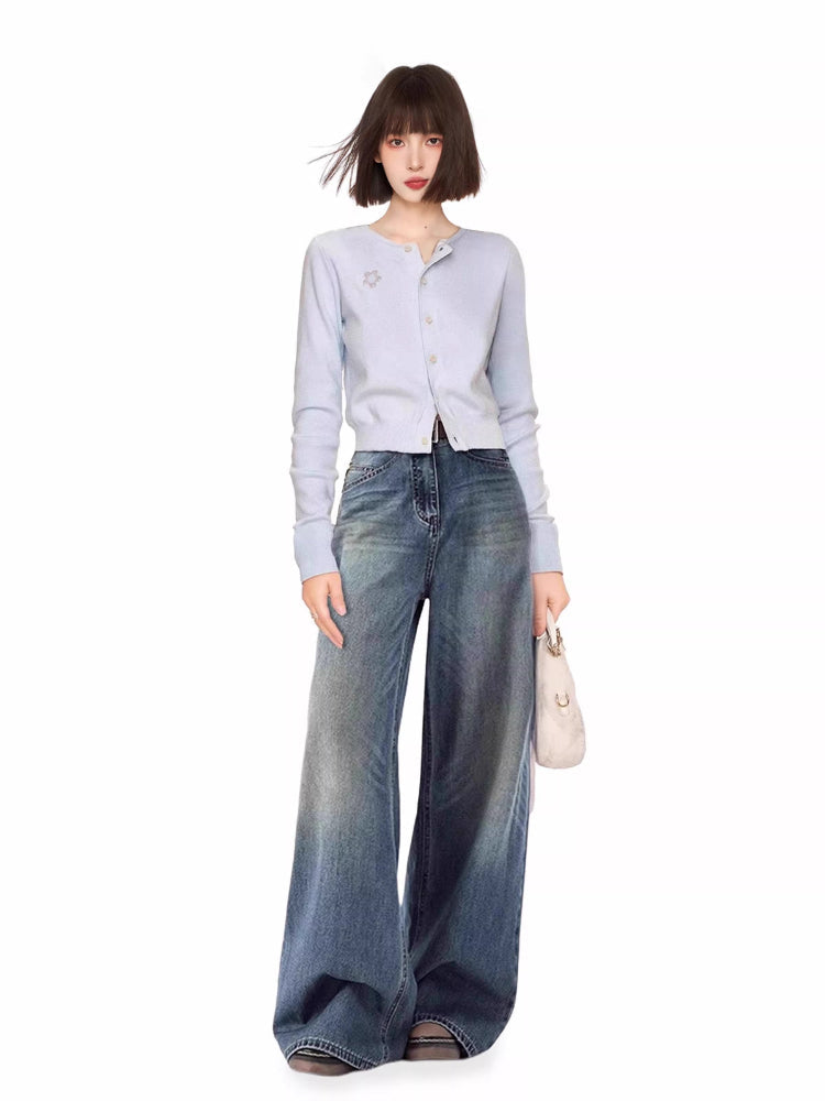 Woman wearing a light blue knit cardigan and wide-leg jeans.