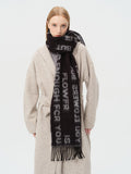 Woman wearing a black scarf with white text print and fringe detail
