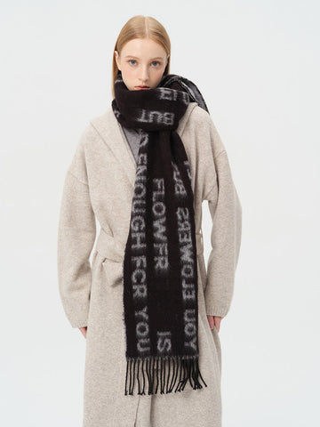 Woman wearing a black scarf with white text print and fringe detail