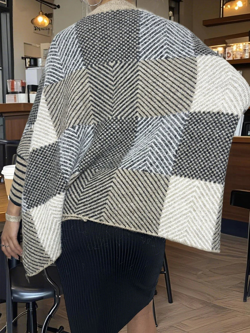 Full body shot of a woman styling a knit poncho with black pants
