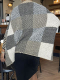 Full body shot of a woman styling a knit poncho with black pants