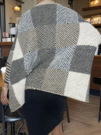 Full body shot of a woman styling a knit poncho with black pants