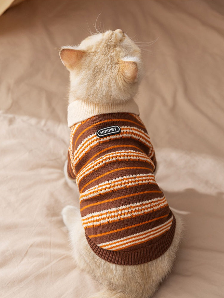 Back view of a cat wearing a brown and orange striped knit sweater with a cream collar and HIPPIPET logo patch.