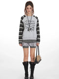 Model wearing a grey graphic print sweatshirt with striped sleeves and shorts.
