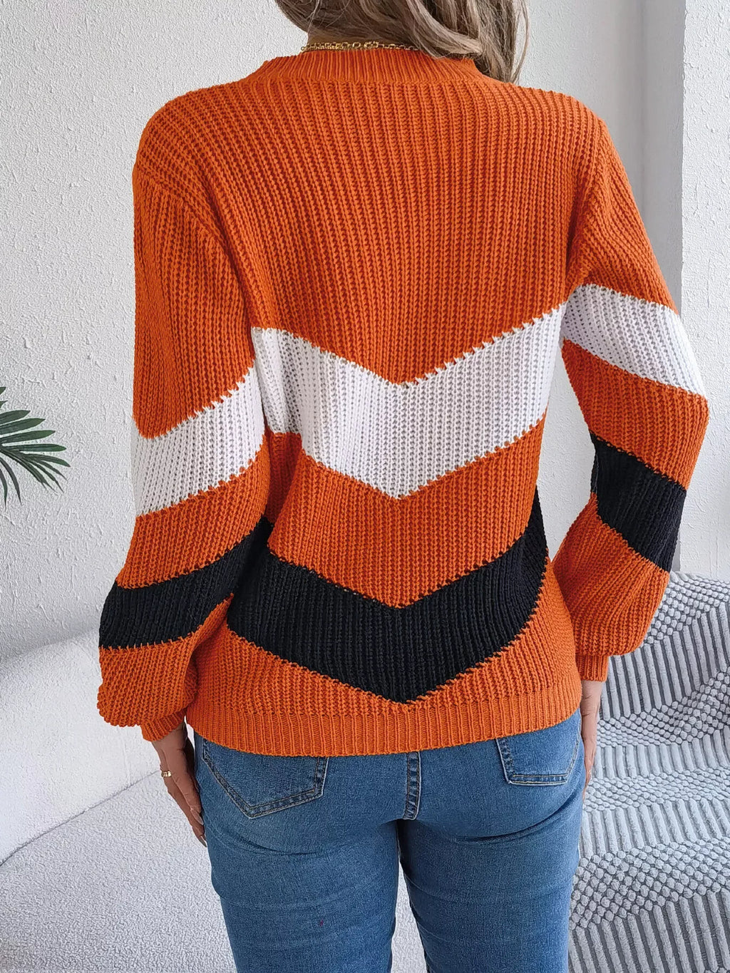 Back view of a woman in an orange, white, and black chevron stripe knit sweater