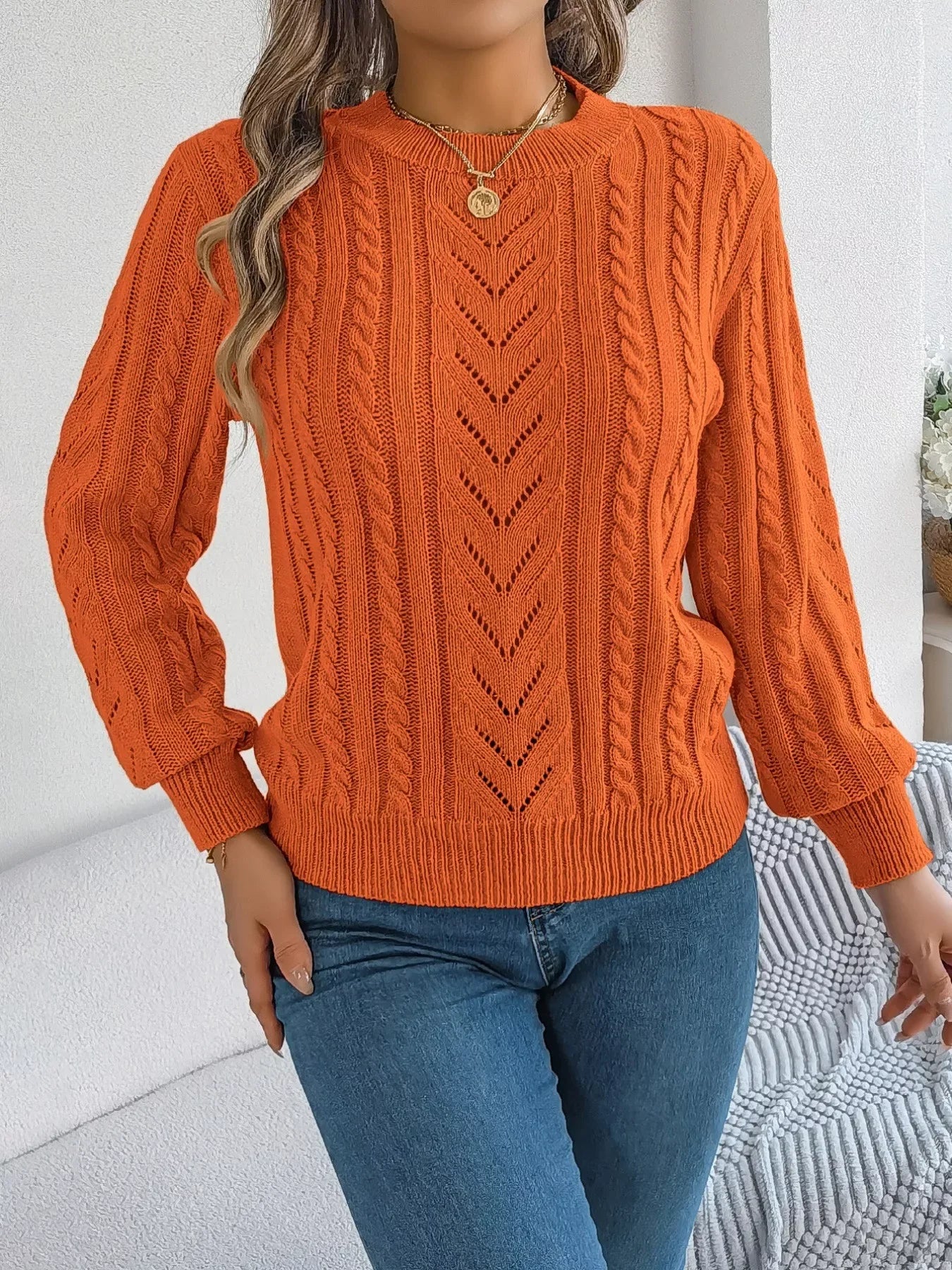 Close-up of the textured knit pattern on an orange sweater worn by a woman.