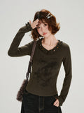 Woman wearing a dark olive long-sleeve graphic t-shirt with ruffled neckline and cuffs.