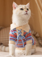 Cat wearing a blue and red striped knit sweater with a lace-up front and cream collar.