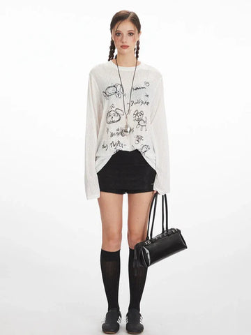 Woman wearing a white long-sleeve sheer knit t-shirt with a black dog graphic print and text, paired with black shorts and black knee-high socks.