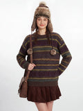 Woman smiling and looking at the camera, wearing a striped sweater and a faux fur hat.