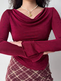 Close-up of a woman wearing a burgundy long-sleeve top with a cowl neckline and ruched side detail.