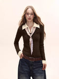 Woman wearing a brown cable knit collared sweater with a white collar and cuffs, paired with dark wash wide-leg jeans and a patterned scarf.