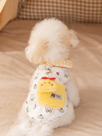 Back view of a white bichon frise dog wearing a white quilted vest with a yellow pocket and cartoon prints