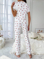 Back view of a woman in a white cherry print pajama set with lace trim.