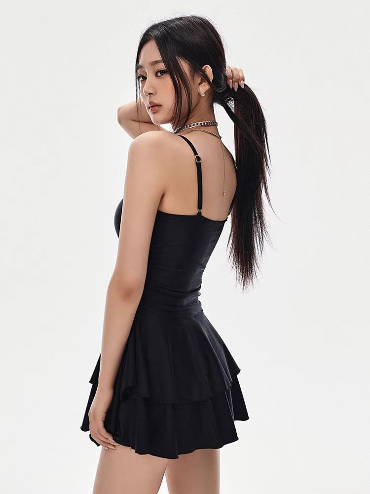 Rear view of a woman wearing a black one-shoulder dress with a tiered skirt
