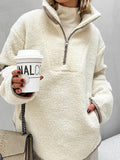 Close-up of a woman wearing a cream sherpa fleece quarter-zip pullover, showing the zipper detail and texture.