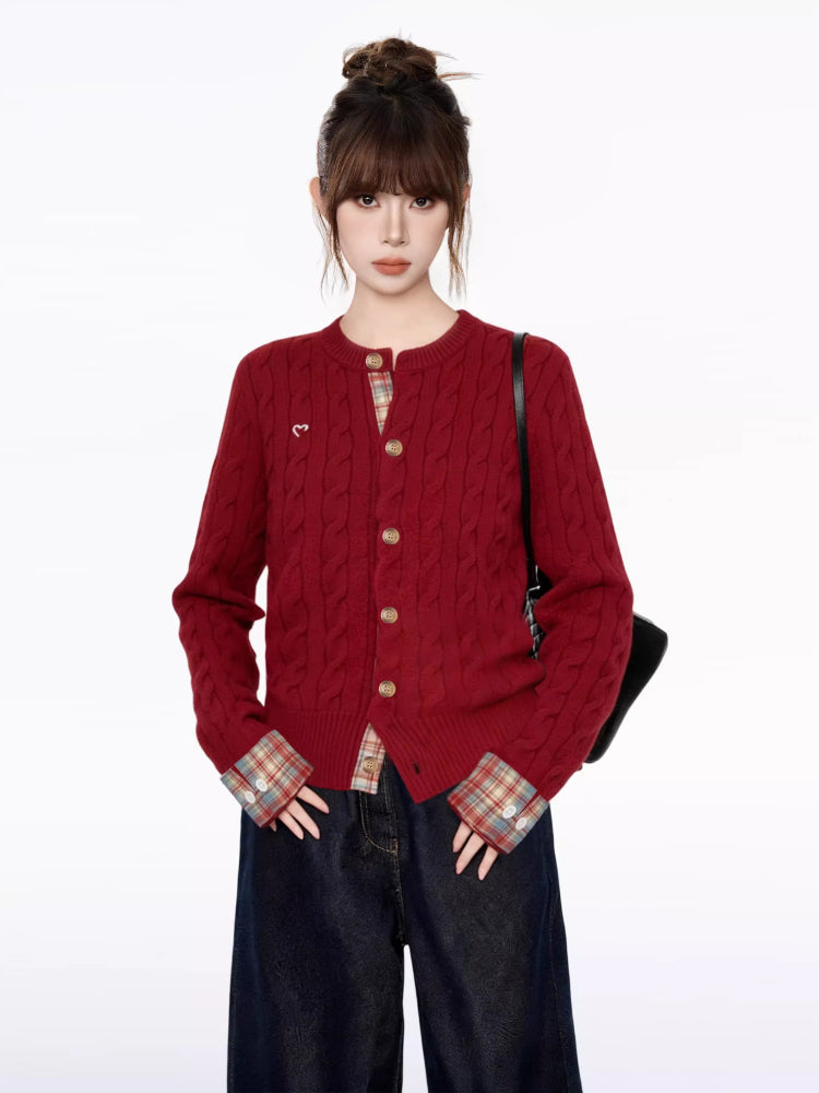 Full body shot of a woman in a red cable knit cardigan with a crew neckline and long sleeves, paired with wide-leg dark wash jeans.