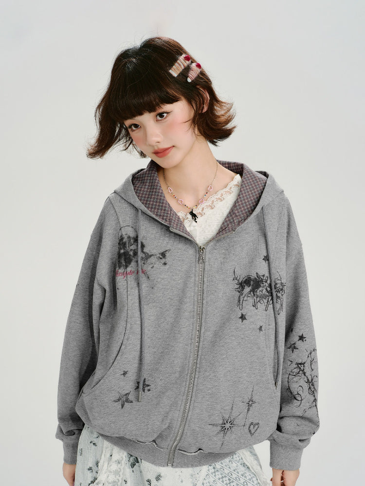 Woman wearing a grey graphic print zip-up hoodie with a checkered interior lining.