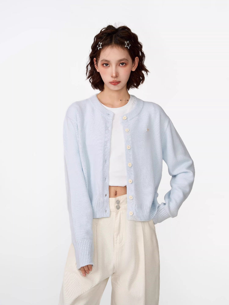 Woman wearing a light blue cropped knit cardigan with a crew neckline and button-front closure.