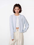 Woman wearing a light blue cropped knit cardigan with a crew neckline and button-front closure.
