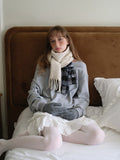 Close-up of a woman wearing a grey sweatshirt and cream scarf