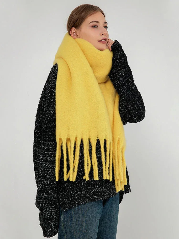 Side profile of a woman showcasing a thick, bright yellow scarf with fringed edges.