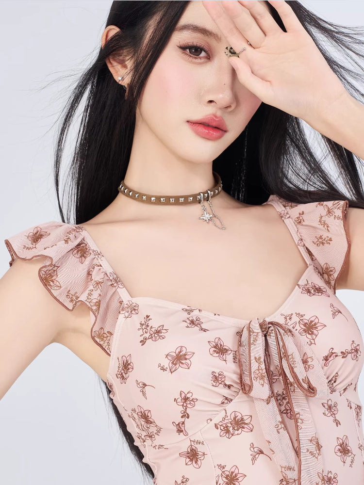 Woman wearing a pink floral print short dress with flutter sleeves and ruffle trim