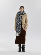 Woman wearing a beige blazer, brown skirt, and a grey and white leopard print fuzzy scarf with fringe trim.