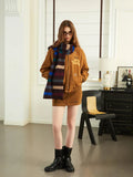 Woman in a brown bomber jacket and mini skirt with a striped scarf, wearing boots
