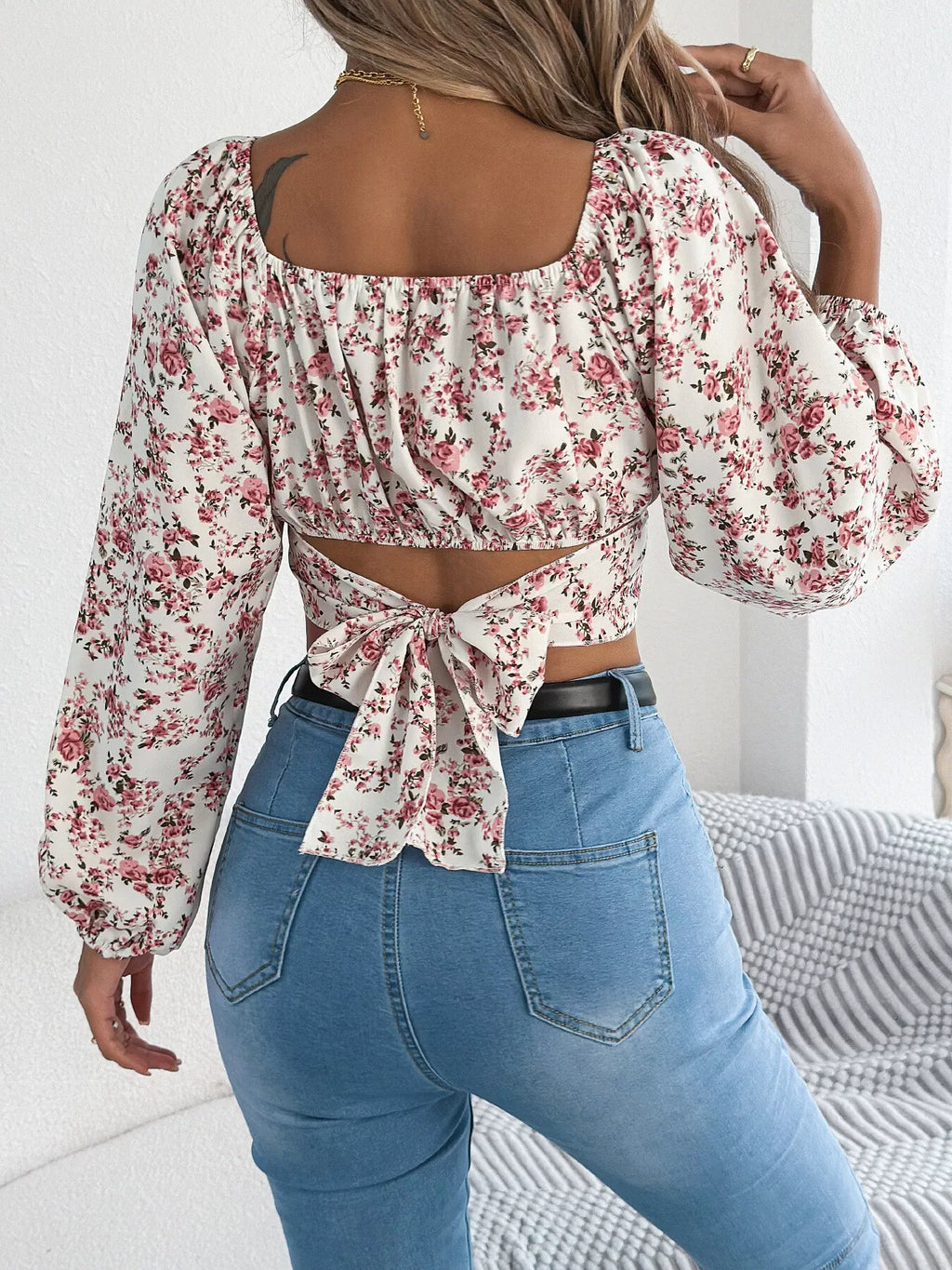 Back view of a woman in a white floral print cropped top with a tie back closure.
