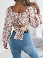 Back view of a woman in a white floral print cropped top with a tie back closure.