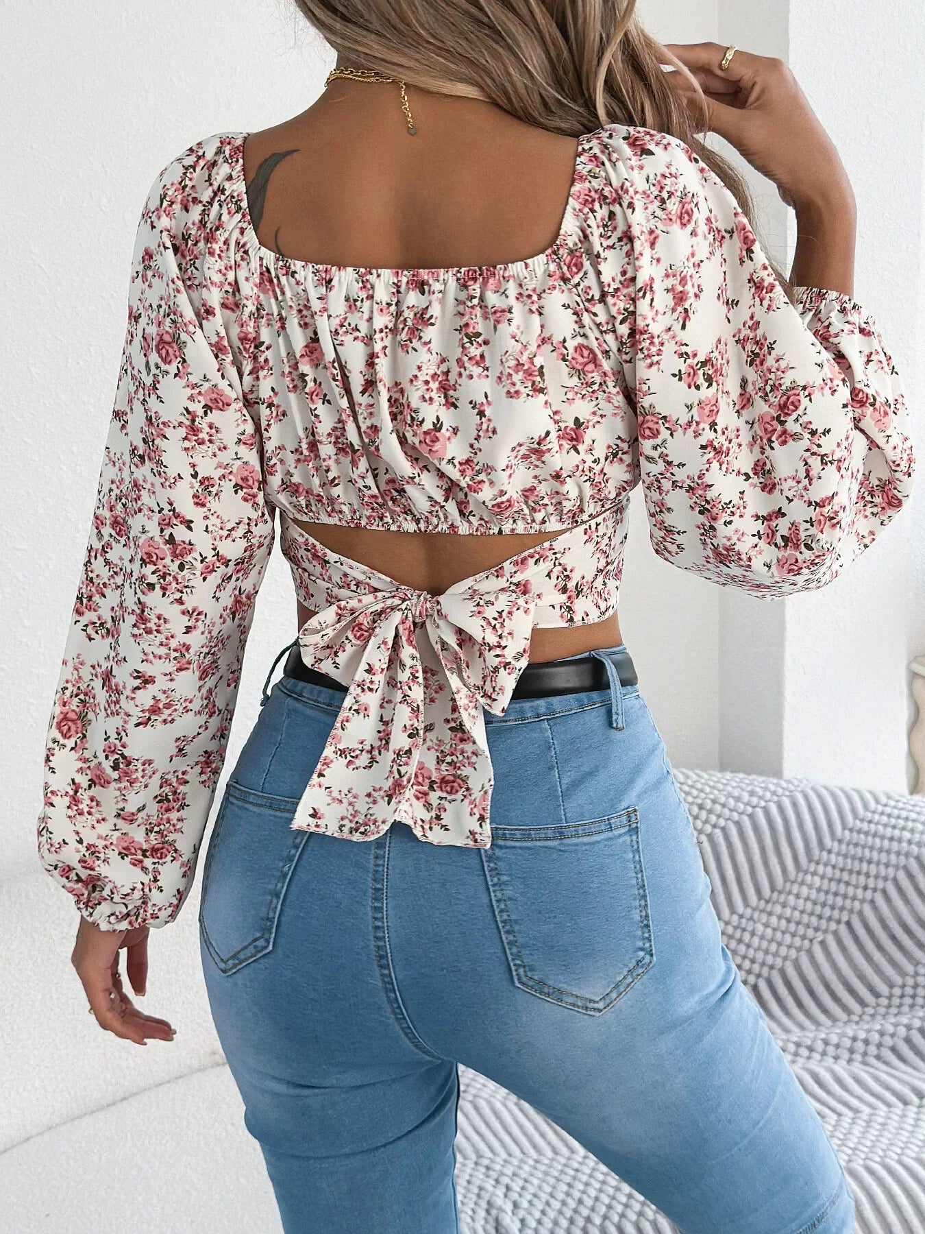 Back view of a woman in a white floral print cropped top with a tie back closure.