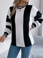 Close-up of a woman wearing a black and white striped knit sweater and blue jeans, with one hand on her hip.