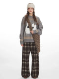 Woman wearing a grey knit sweater with a graphic sheep print and plaid wide leg pants, holding a faux fur bag.