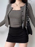 Woman in a black and white houndstooth set with a black skirt and handbag.