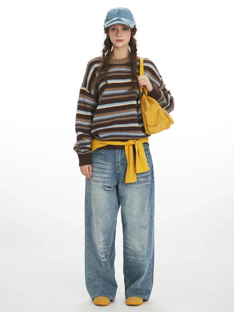 Woman wearing a brown, blue, and yellow striped knit sweater with a crew neck and long sleeves.