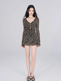 Full-length view of a model in a black and gold striped sheer mesh mini dress, showcasing the fit-and-flare silhouette.