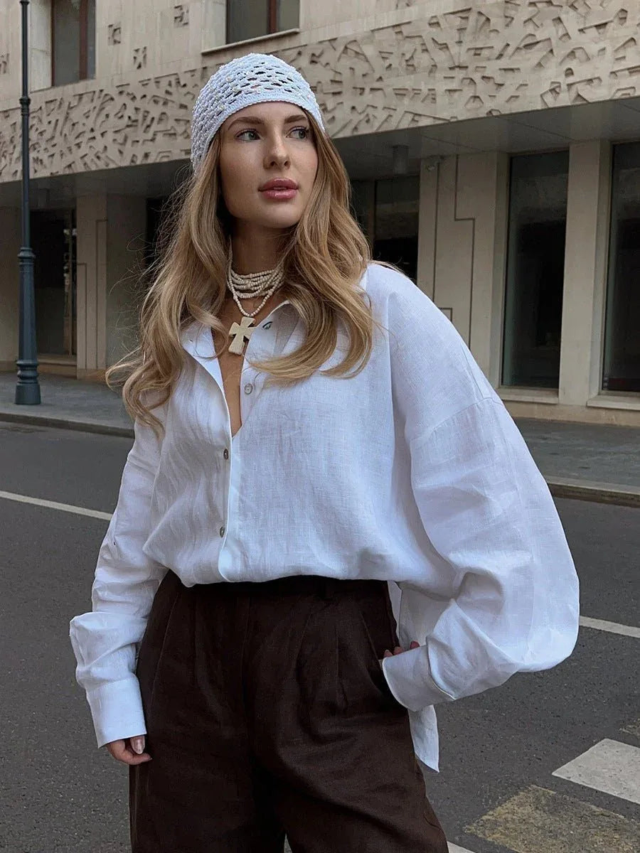 Woman in white oversized cotton button down shirt and brown trousers