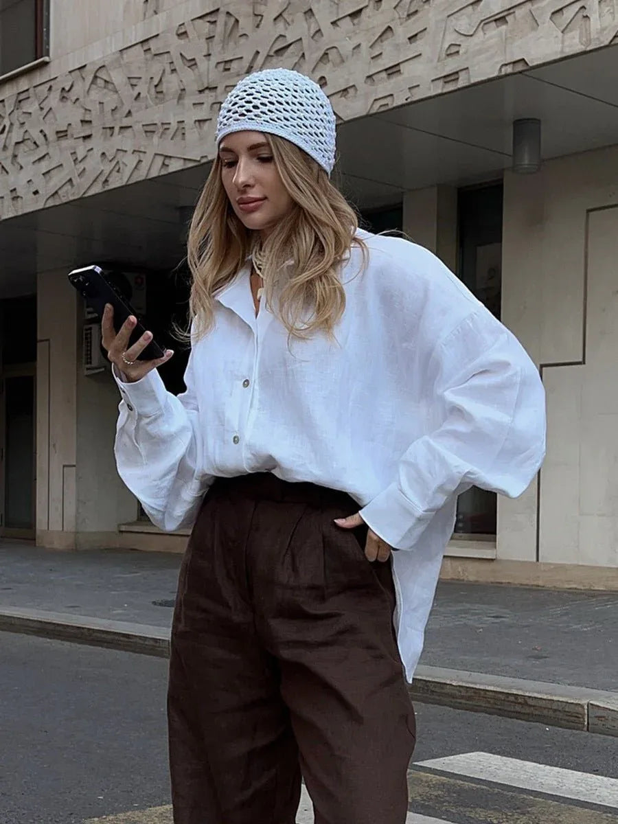 Woman in white oversized cotton shirt looking at her phone