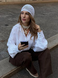 Woman sitting on a ledge in a white oversized cotton shirt